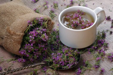 Yaz şifalı bitkiler. Tahta masadaki kekik çayı. Yakın çekim. Taze kekik çiçekleri çay süzgecinde