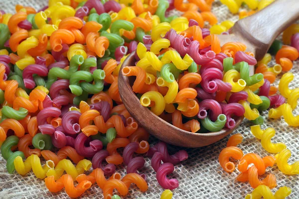 在木制桌子上的勺子里放着五颜六色的意大利面 有机天然健康食品 带有天然染料的彩色面食 — 图库照片