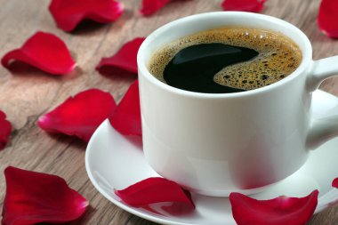 Romantik kahve. Not: Seni seviyorum, masada bir fincan kahve ve kırmızı gül yaprakları. Beyaz fincanda kahve ve gül yaprakları. en üstteki görünüm