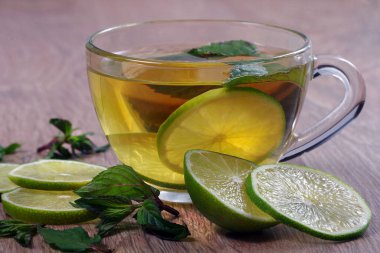Nane ve limonla ferahlatıcı bir içecek. Tahta bir masada limonlu bir fincan nane çayı..