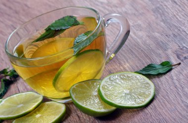 Nane ve limonla ferahlatıcı bir içecek. Tahta bir masada limonlu bir fincan nane çayı..