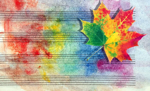 Colors of rainbow. Melody concept. Old music sheet in colorful watercolor paint and fallen maple leaf. Music concept. Abstract colorful watercolor background. Autumn melody
