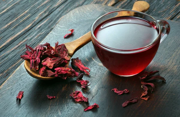 hibiscus tea. dry hibiscus petals in a wooden spoon on the table. vitamin drink for flu and colds
