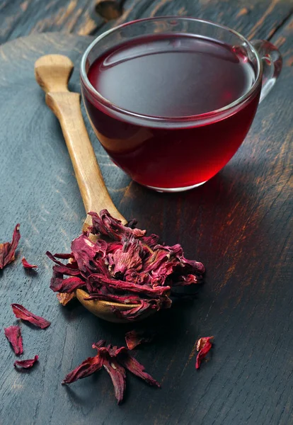 hibiscus tea. dry hibiscus petals in a wooden spoon on the table. vitamin drink for flu and colds