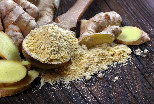 fresh ginger root and dry ground ginger in a wooden spoon. powder ginger close-up