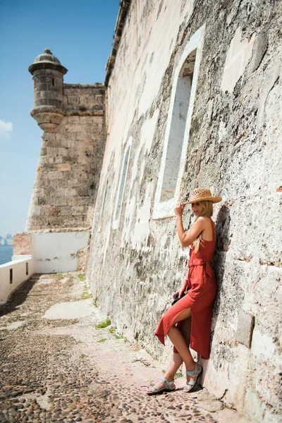 Young woman with hat standing near old fortress