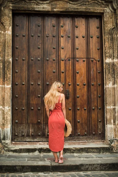 Büyük eski kapının yanında duran şapkalı genç kadın.