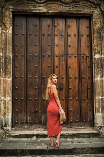 Büyük eski kapının yanında duran şapkalı genç kadın.