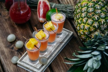 Ahşap masada ananaslı renkli kokteyller.