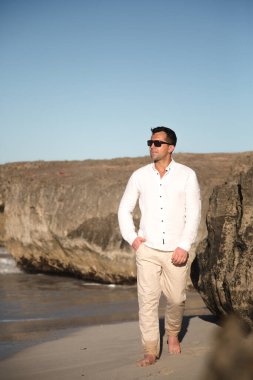 Sahilde güneş gözlüklü genç adam.