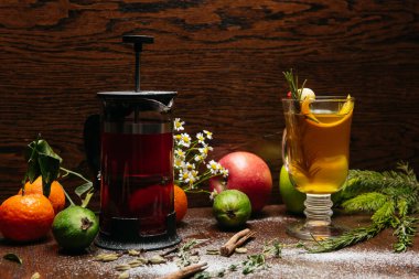 Fransız presi ve şeffaf fincanda narenciye çayı ve restorandaki masada elma ve liçi.