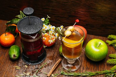 Fransız presi ve şeffaf fincanda narenciye çayı ve restorandaki masada elma ve liçi.