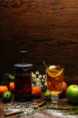 Fransız presi ve şeffaf fincanda narenciye çayı ve restorandaki masada elma ve liçi.