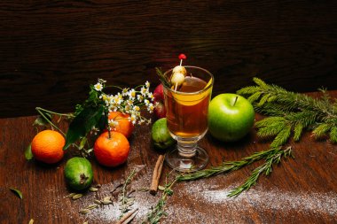 Şeffaf bardakta narenciye çayı ve restorandaki masada elma ve liçi.