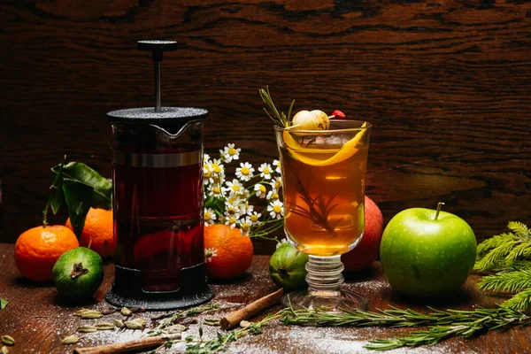 Fransız presi ve şeffaf fincanda narenciye çayı ve restorandaki masada elma ve liçi.