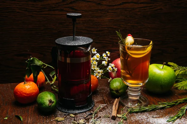 Fransız presi ve şeffaf fincanda narenciye çayı ve restorandaki masada elma ve liçi.