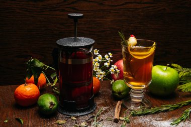 Fransız presi ve şeffaf fincanda narenciye çayı ve restorandaki masada elma ve liçi.