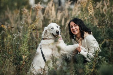   Brunette girl with white golden retriever dog in the field