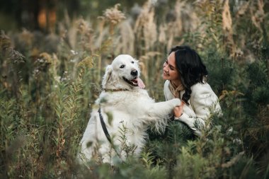   Brunette girl with white golden retriever dog in the field