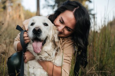 Golden Retriever köpeğini kucaklayan bir kız.