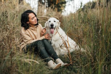   Esmer kız ve beyaz golden retriever köpeği orman yolunda