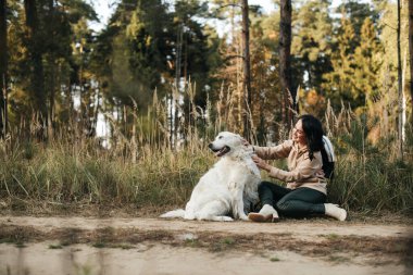 Esmer kız ve beyaz golden retriever köpeği orman yolunda