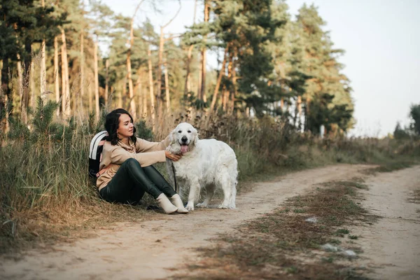 在田野里抱着一只金毛猎犬的女孩 — 图库照片