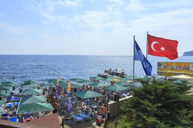 Kemer, Turkey - 19 Haziran 2018: Plaj şemsiyeleri ve Resort Kemer, Türkiye'de Türk bayrağı