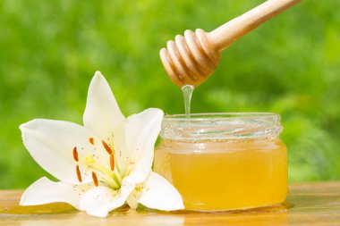 Bal kavanozu, sopa ve lily çiçek.