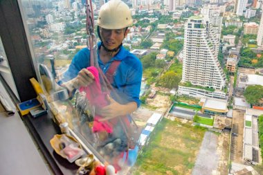Bangkok, Tayland - 13 Aralık 2018: Yüksek doğmak pencere temizlik - bir cesur meslek. Bir pencere temizleyici korkusuzca windows yüksek artış binanın temizlik onun halatlar üzerinde asılı.