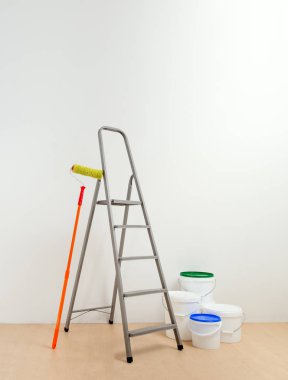 boyama aracı (boya silindiri; adım-merdiven kovası;) beyaz odada. Kavramı boya duvarlar