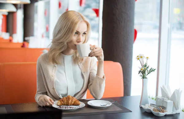 カフェで食べるクロワッサン コーヒーまたは紅茶 水平縦美しい 幸せな 若い女性が座っています — ストック写真