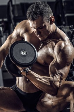 vücut geliştirmeci adam, koyu spor salonunda egzersiz halter ile gerçekleştirmek