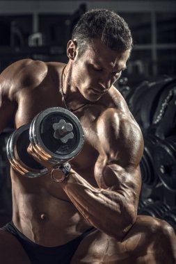 vücut geliştirmeci adam, koyu spor salonunda egzersiz halter ile gerçekleştirmek