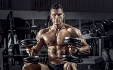 vücut geliştirmeci adam, koyu spor salonunda egzersiz halter ile gerçekleştirmek