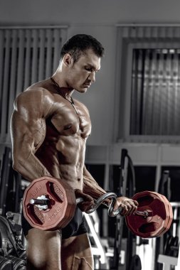 vücut geliştirmeci adam, koyu spor salonunda egzersiz halter ile gerçekleştirmek