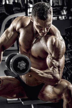 vücut geliştirmeci adam, koyu spor salonunda egzersiz halter ile gerçekleştirmek