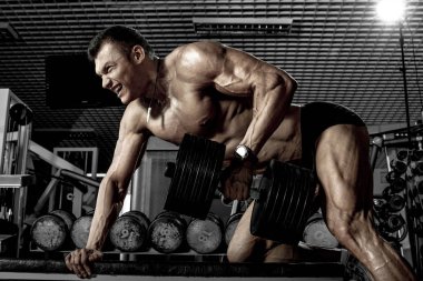 vücut geliştirmeci adam, bir geri, koyu spor salonu geniş kas egzersiz halter ile gerçekleştirmek