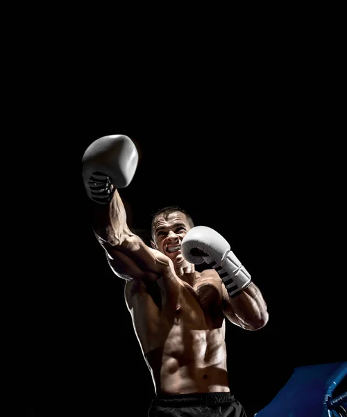 punching boxer on boxing ring, black background, vertical photo