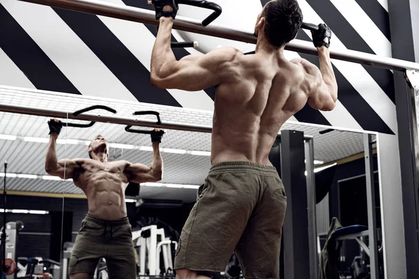 guy bodybuilder , perform exercise do chin-ups, horizontal bar in gym, horizontal photo
