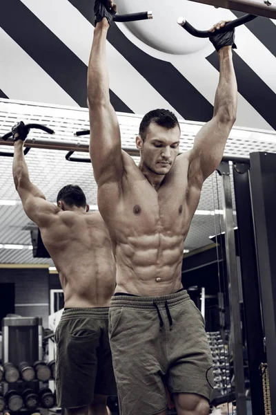 guy bodybuilder , perform exercise do chin-ups, horizontal bar in gym, vertical photo