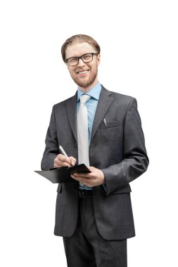 Gözlüklü bir işadamı ya da ofis çalışanı beyaz arka planda defter ve gülümsemeyle dikiliyor.