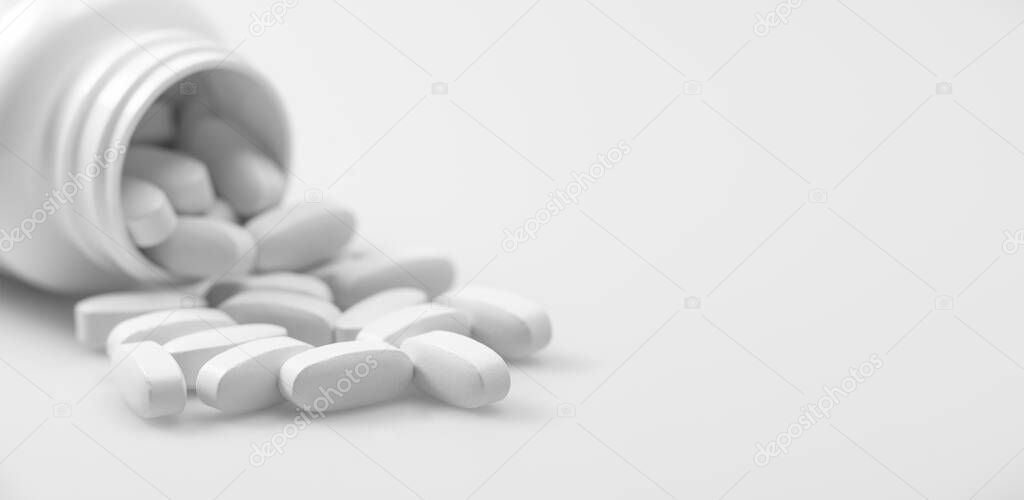 jar with scattered group white medical pill closeup on whie background