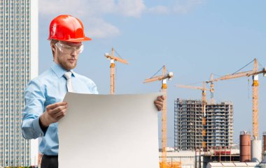 Akıllı bir mimar işçisinin portresi ya da inşaat alanında çizim yapan kırmızı miğferli mühendis. İnşa kavramı