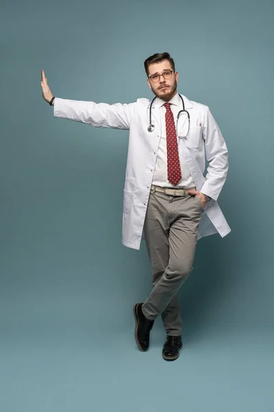 Un retrato de un médico posando sobre fondo gris — Foto de Stock