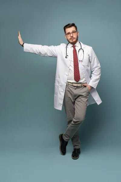 Um retrato de um médico posando contra fundo cinza — Fotografia de Stock