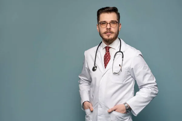 Um retrato de um médico posando contra fundo cinza — Fotografia de Stock