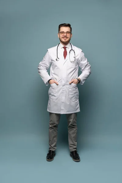 Ett porträtt av en läkare poserar mot grå bakgrund — Stockfoto