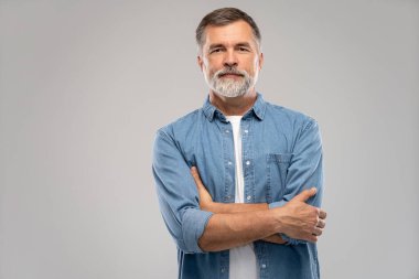 Beyaz arka planda duran gülümseyen olgun bir adamın portresi.