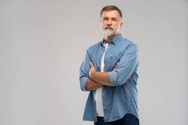 Beyaz arka planda duran gülümseyen olgun bir adamın portresi.